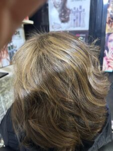 Hair transformation at a beauty salon in New Cairo showing soft layered styling with light brown highlights and natural shine, created by Sanaa Ahmed Beauty Salon for women looking for professional hair color and styling services in Cairo